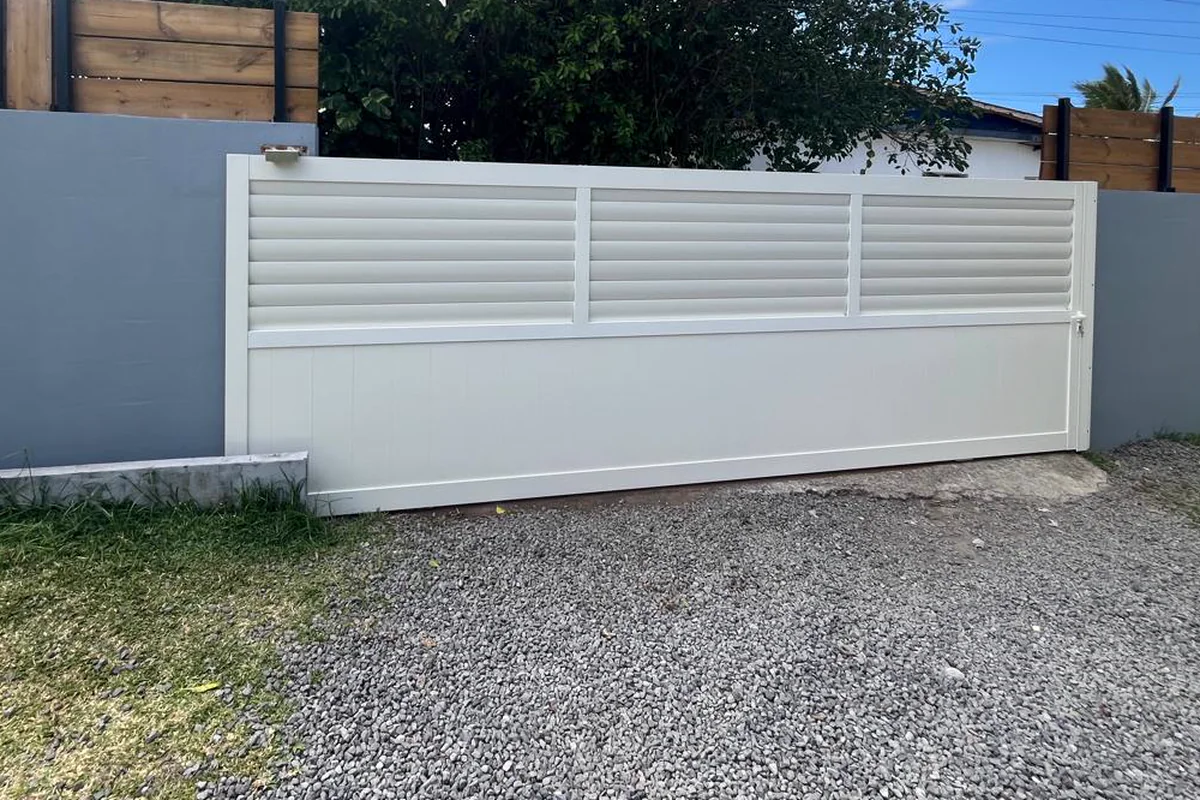 Portail coulissant aluminium blanc à lames et soubassement plein