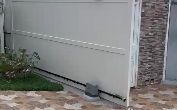 Moteur électrique et crémaillère au pied d'un portail coulissant aluminium blanc